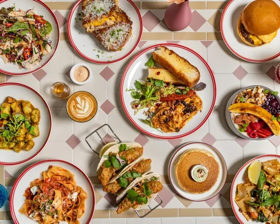 A spread of Zee's Cafe's signature dishes: tacos, pancakes, salads, coffee and burgers laid out on the table