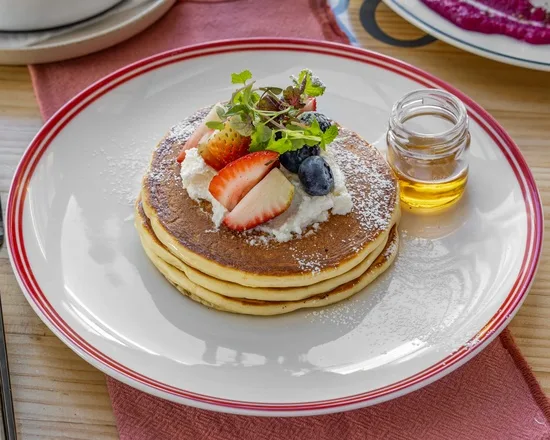 A stack of sweet-style pancakes with fresh berries, mint and maple at Zee's Cafe